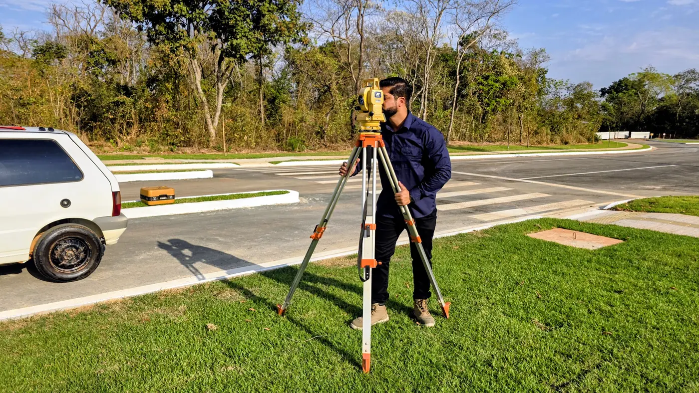 Topógrafo da RS Topografia operando estação total em avenida de loteamento