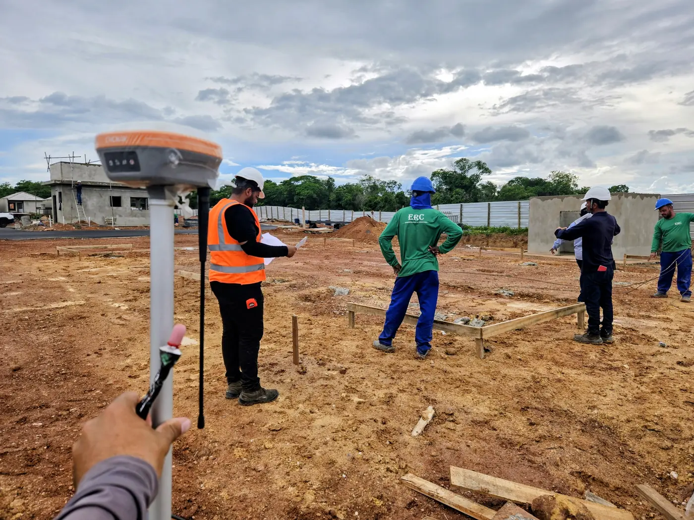 Topógrafo em canteiro de obra ao lado da equipe da construtora