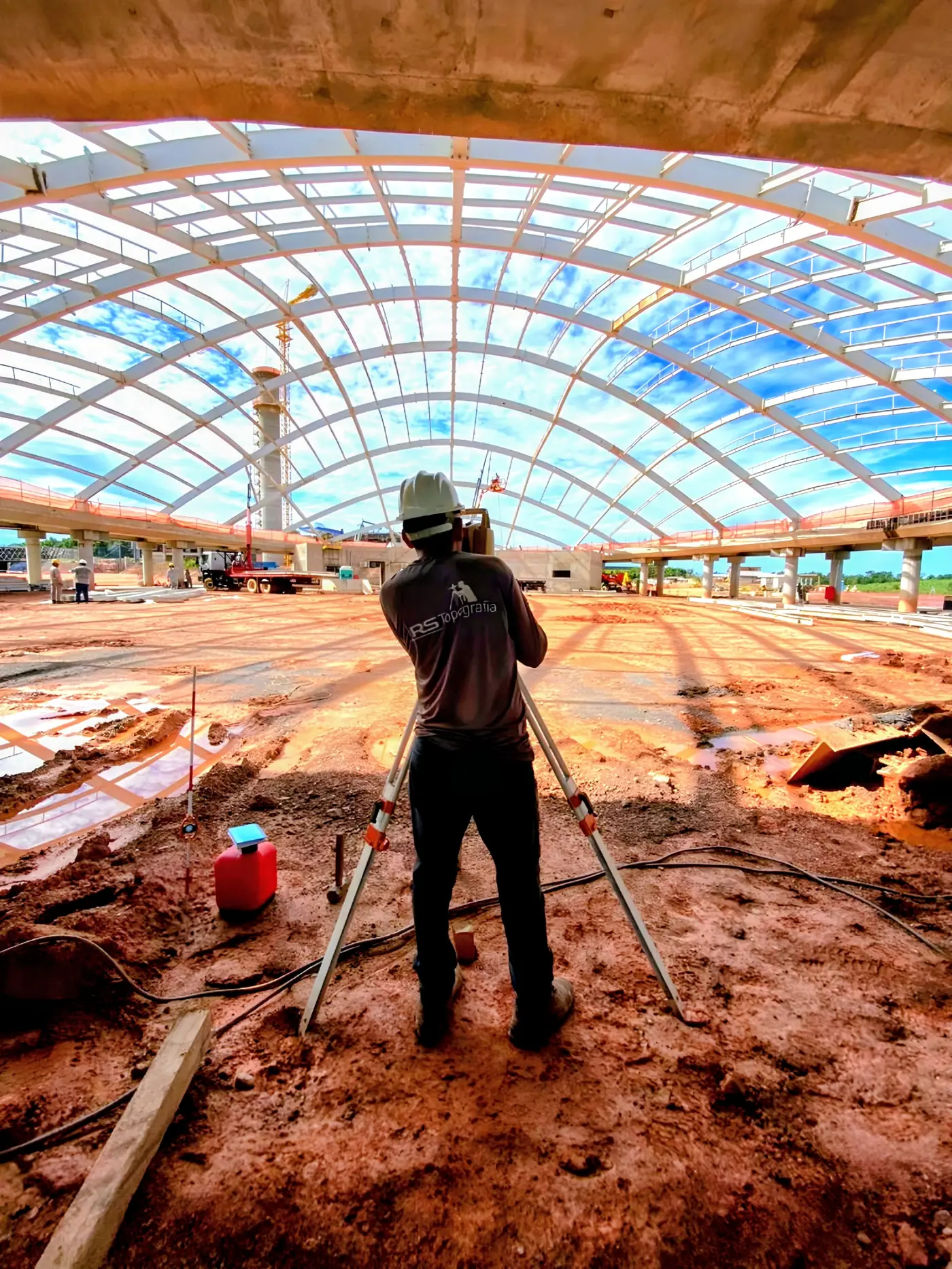 Topógrafo da RS Topografia operando estação total sob a cobertura metálica de uma obra de grande porte